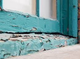 Weathered door step that has teal blue paint which you can tell is lead based because it is peeling off. Reusing building material is prohibited for lead based paint